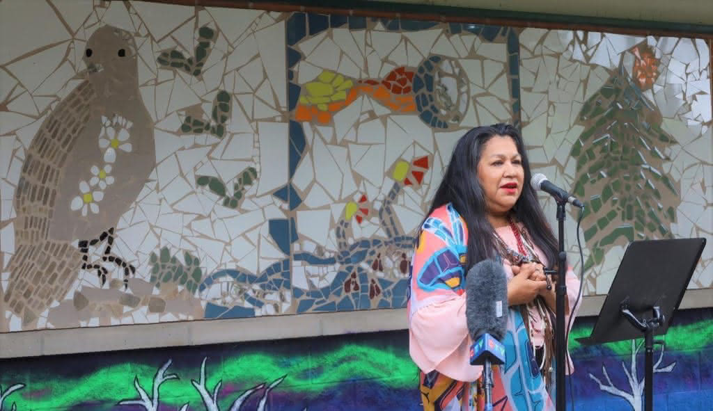 Photo of Miskwi mural and artist Doreen Stevens